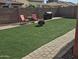 Inviting backyard with artificial grass, brick-lined patio, comfortable seating, and a barbecue grill for outdoor enjoyment at 36119 W Catalan St, Maricopa, AZ 85138