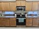 Functional kitchen with wooden cabinets, stainless steel appliances, and a stove with overhead microwave at 36119 W Catalan St, Maricopa, AZ 85138