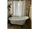 Bathroom featuring a clawfoot tub, glass block window and neutral tiling and decorative curtains at 3811 E Evans Dr, Phoenix, AZ 85032