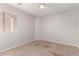 Bedroom with neutral colored walls, ceiling fan, carpeted floor, and a view to the back yard at 5675 S 239Th Ln, Buckeye, AZ 85326