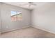 Cozy bedroom featuring neutral walls, carpeted floors, ceiling fan, and view to outside at 5675 S 239Th Ln, Buckeye, AZ 85326