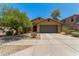 Inviting single-story home with a two-car garage, desert landscaping, and mature trees at 7003 S 23Rd Ln, Phoenix, AZ 85041