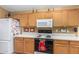 Functional kitchen featuring an oven, microwave, white refrigerator, and wood cabinets at 7003 S 23Rd Ln, Phoenix, AZ 85041