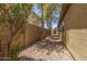 Practical side yard with gravel, mature trees, and a sturdy block wall for privacy at 7003 S 23Rd Ln, Phoenix, AZ 85041