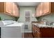 Functional laundry room with wood cabinets, granite counters, modern washer and sink at 8540 W Wescott Dr, Peoria, AZ 85382