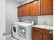 Functional laundry room with wood cabinets, a utility sink, and modern washer and dryer units at 10236 W Wood St, Tolleson, AZ 85353