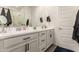 Bright bathroom with a double sink vanity with white countertops and cabinets and black hardware at 12505 W Kaler Dr, Glendale, AZ 85307