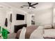 Bright main bedroom featuring a ceiling fan, television, ensuite bathroom and plush carpet at 12505 W Kaler Dr, Glendale, AZ 85307