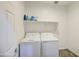 Efficient laundry room with a full-size washer and dryer, complemented by overhead shelving for storage at 12515 W Marguerite Ave, Avondale, AZ 85323