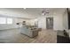 Spacious living room with wood-style tile flooring next to the kitchen with white cabinets at 12515 W Marguerite Ave, Avondale, AZ 85323
