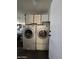 Laundry room with modern front-loading washer and dryer set, complemented by upper cabinet storage space at 13037 W Laurel Ln, El Mirage, AZ 85335