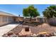 Spacious backyard featuring desert landscaping, mature shade tree, block fencing, and outdoor seating area at 1376 E Rosemary Trl, Casa Grande, AZ 85122