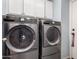 Laundry room equipped with modern gray front-loading washer and dryer and white cabinets at 1376 E Rosemary Trl, Casa Grande, AZ 85122