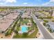 Aerial view of community pool with palm trees, green grass, lounge chairs, and surrounding houses at 14075 W Desert Flower Dr, Goodyear, AZ 85395