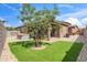 Manicured backyard with artificial grass, shade tree, rock landscaping, patio and hot tub create a private oasis at 14075 W Desert Flower Dr, Goodyear, AZ 85395