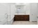 A modern bathroom featuring a soaking tub with glass doors, dark wood vanity, and tile flooring at 14075 W Desert Flower Dr, Goodyear, AZ 85395