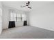 Cozy bedroom with soft carpet, a black ceiling fan, and a window with sheer white and black curtains at 14075 W Desert Flower Dr, Goodyear, AZ 85395
