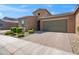 Exterior view of a single story home featuring a paved driveway, green shrubs, and a two-car garage at 14075 W Desert Flower Dr, Goodyear, AZ 85395