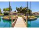 Picturesque wooden bridge over a blue lagoon, leading to charming homes within a lush community at 14561 W Winding Trl, Surprise, AZ 85374