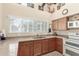 Kitchen features wood cabinets, oven, cooktop, microwave and large window for natural light at 14561 W Winding Trl, Surprise, AZ 85374