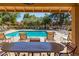 Relaxing poolside view from covered patio seating, overlooking the community pool surrounded by trees at 14561 W Winding Trl, Surprise, AZ 85374