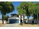 Charming two-story home with a blue garage door, mature trees, and well-maintained landscaping at 14922 N 172Nd Dr, Surprise, AZ 85388