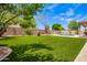 Spacious backyard featuring a pristine lawn and outdoor living space with lush landscaping and privacy at 17853 W Pershing St, Surprise, AZ 85388