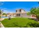 Expansive backyard with lush green lawn, mature trees, and outdoor patio area at 17853 W Pershing St, Surprise, AZ 85388