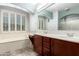 Bathroom showcasing double sink vanity, tile flooring, tub, and window with shutters at 17853 W Pershing St, Surprise, AZ 85388