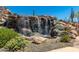 Scenic waterfall cascading over rocks, surrounded by lush greenery and cacti, offering a peaceful retreat at 1854 W Fetlock Trl, Phoenix, AZ 85085