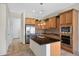 The kitchen has granite counters, an island with a sink, wooden cabinets, and stainless steel appliances at 20082 N 272Nd Ln, Buckeye, AZ 85396