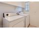 A laundry room with a window, includes both a washing machine and a clothes dryer, and shelving above at 2862 E Megan St, Gilbert, AZ 85295