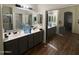 Bathroom with double sinks, mirrored closet, hardwood floors, and a large mirror at 2981 S 257Th Ave, Buckeye, AZ 85326