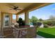 Covered patio with fan and outdoor dining, overlooking a beautiful pool and yard at 31221 N 130Th Ln, Peoria, AZ 85383
