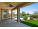 Covered patio with fan overlooking a beautiful pool and landscaped backyard at 31221 N 130Th Ln, Peoria, AZ 85383