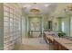 Bright bathroom with glass block wall, soaking tub, double vanities, and neutral tile floors at 42101 N Olympic Fields Ct, Anthem, AZ 85086