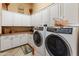 Laundry room featuring white cabinets, a sink, countertop and modern washer and dryer at 42101 N Olympic Fields Ct, Anthem, AZ 85086