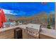Backyard outdoor kitchen with grill, bar seating, and pool in the distance at 42101 N Olympic Fields Ct, Anthem, AZ 85086