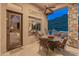 Covered patio with stone columns, outdoor dining set, and views of the pool and desert landscape at 42101 N Olympic Fields Ct, Anthem, AZ 85086