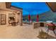 Outdoor patio with stone columns, covered seating, built-in grill, and view of the inviting pool and desert landscape at 42101 N Olympic Fields Ct, Anthem, AZ 85086
