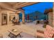 Spacious covered patio with stone columns, ceiling fan, outdoor seating, and view of the inviting pool and desert landscape at 42101 N Olympic Fields Ct, Anthem, AZ 85086