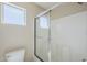 Bright bathroom featuring a glass shower stall and toilet underneath a sunny window at 43205 W Oster Dr, Maricopa, AZ 85138