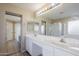 Elegant bathroom with double sinks, white cabinetry, and a large mirror, leading to a shower at 43205 W Oster Dr, Maricopa, AZ 85138