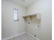 Functional laundry room featuring tile flooring, a small window, and a convenient built-in shelf for storage at 43205 W Oster Dr, Maricopa, AZ 85138