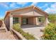 Relaxing covered patio complemented by colorful landscaping and sliding glass doors leading to the home's interior at 4853 N 183Rd Ln, Goodyear, AZ 85395