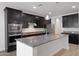 Modern kitchen showcasing a granite island, stainless steel appliances, and dark wood cabinets for an elegant design at 4853 N 183Rd Ln, Goodyear, AZ 85395