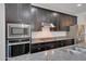 Close-up of a kitchen island with stainless steel appliances, dark cabinets, and stone countertops at 4853 N 183Rd Ln, Goodyear, AZ 85395