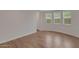 Bright, empty room with wood-look floors, baseboards, multiple windows, and a door at 4853 N 183Rd Ln, Goodyear, AZ 85395