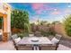 Cozy backyard patio with a stone table, chairs, string lights, and green landscaping at 4960 E Colonial Dr, Chandler, AZ 85249