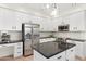 Well-equipped kitchen boasts stainless steel appliances, black granite countertops, a center island, and white cabinets at 4960 E Colonial Dr, Chandler, AZ 85249